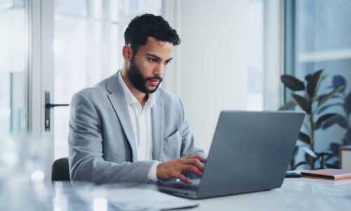 Laptop, research and businessman by desk in office for budget report, planning or feedback on email. Corporate, employee and financial planner with tech for investment, review or reading finance news